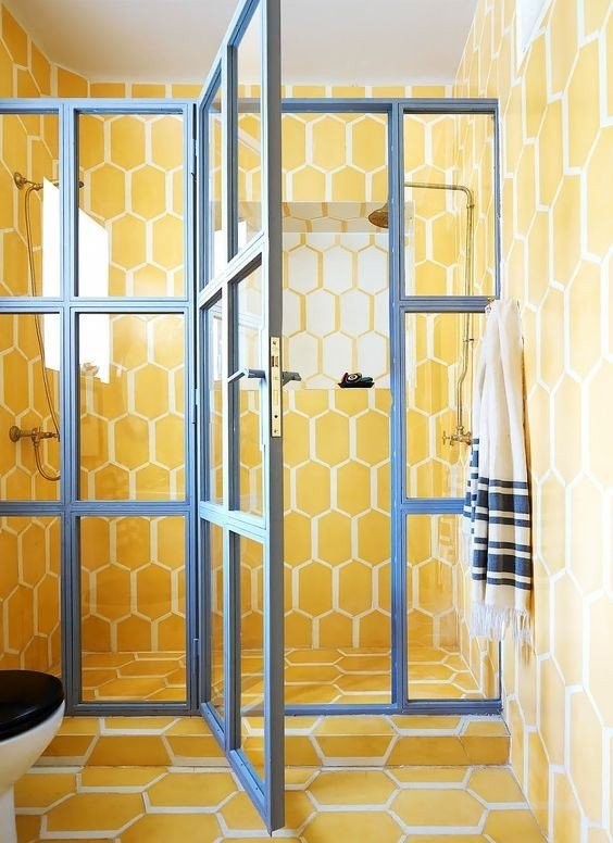 04-a-super-bright-yellow-tile-bathroom-with-a-glazed-shower-door-with-blue-framing-for-a-contrasting-look.jpg