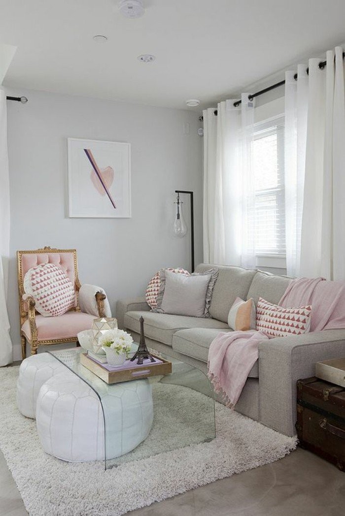 neutral-colors-light-living-room-pale-gray-couch-pale-pink-throw-blanket-grey-white-and-pink-pillows-two-white-leather-bean-bags-clear-glass-table-pink-chair-with-gold-details-off-white-walls.jpg