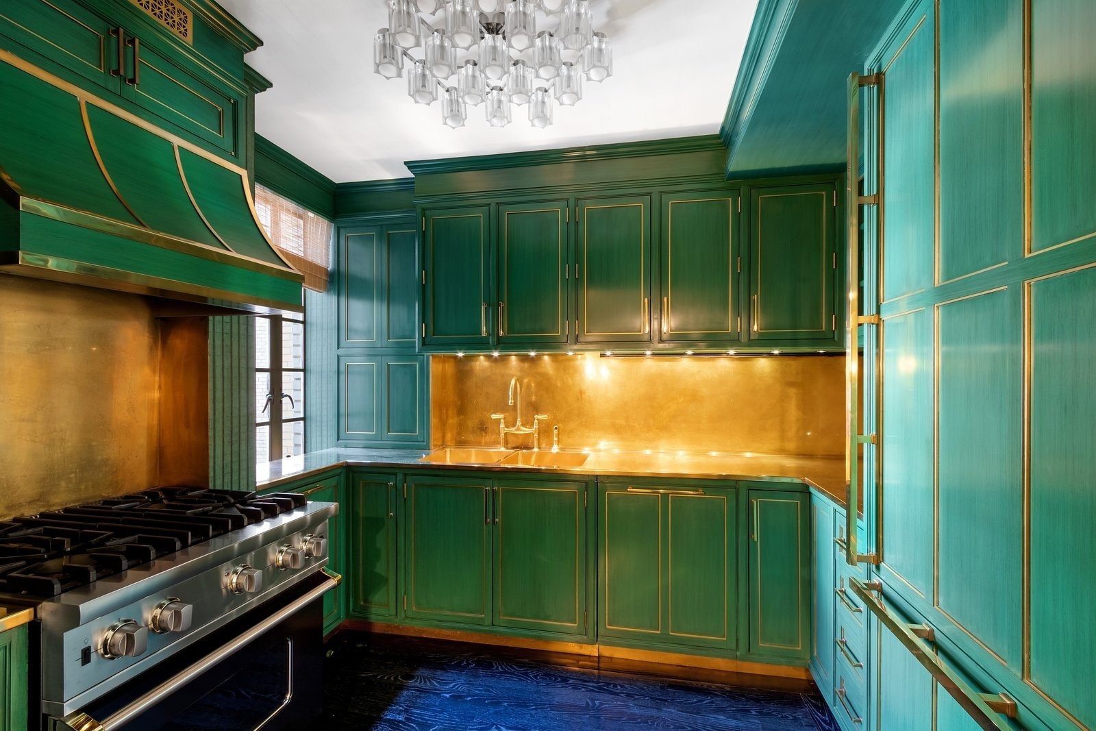 the-chefs-kitchen-is-fitted-with-a-miele-dishwasher-a-sub-zero-refrigeratorfreezer-a-viking-range-and-a-water-filtration-system-the-emerald-cabinets-are-accented-by-the-brass-backsplash-hardware-and-counters.jpg