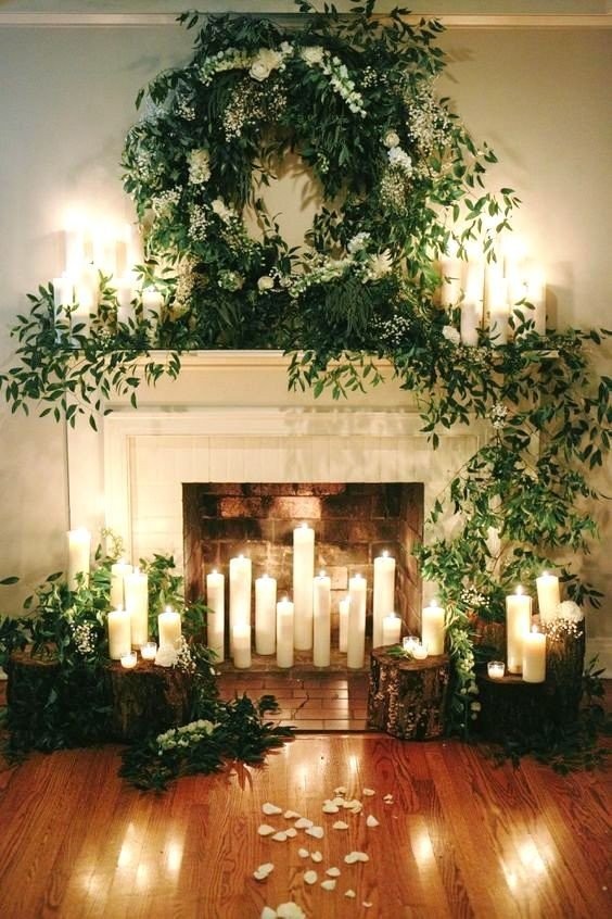 02-a-beautiful-fireplace-with-candles-inside-around-and-on-the-mantel-with-lush-greenery-and-white-blooms.jpg