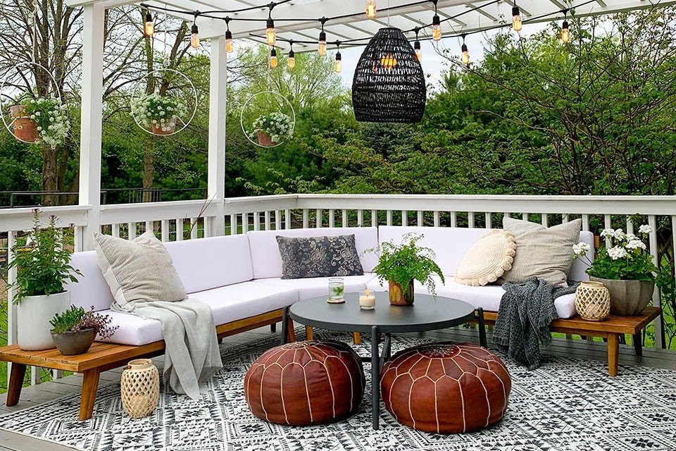 black-and-white-geometric-outdoor-rug-with-white-and-brown-couch-and-leather-brown-ottoman-with-plants-and-lights.jpg